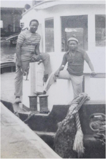 Black and white poto of two men posing on a boat's deck